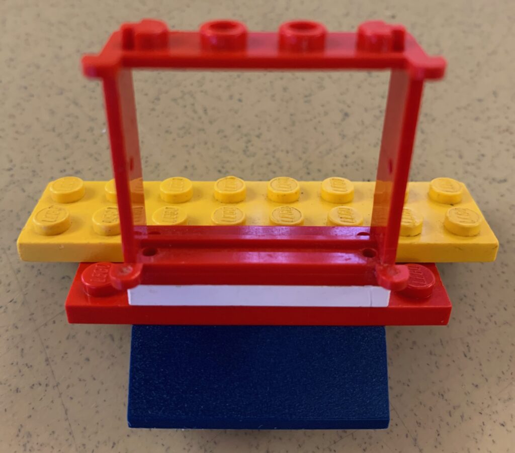 A lego representation built in response to the prompt: What would you like your colleagues who didn't attend this retreat to know about DEI in the Gen Ed, depicting a wide open doorway with an onramp and gold on the other side.
