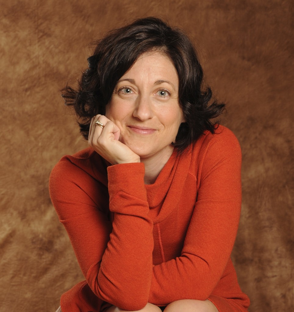 Robin DeRosa headshot - a white woman with dark shoulder-length hair, facing the camera, with chin in hand in a relaxed yet alert position, bright eyes, and a closed-mouth smile.