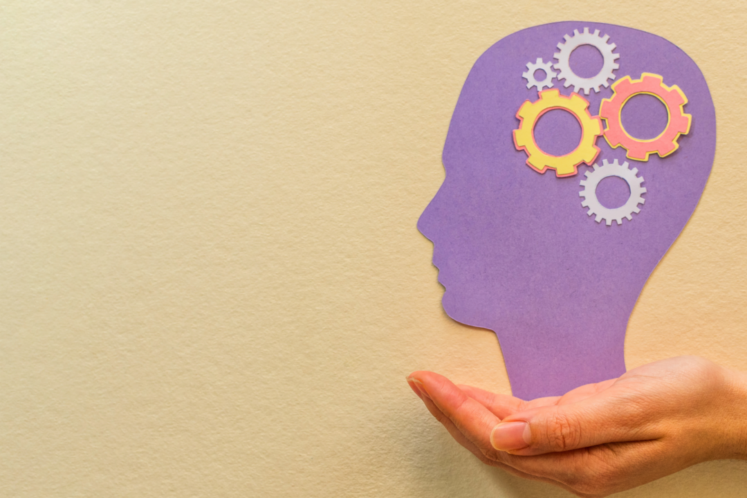 An abstract purple head with gears in the location of the brain being held in the palm of a person's hand.